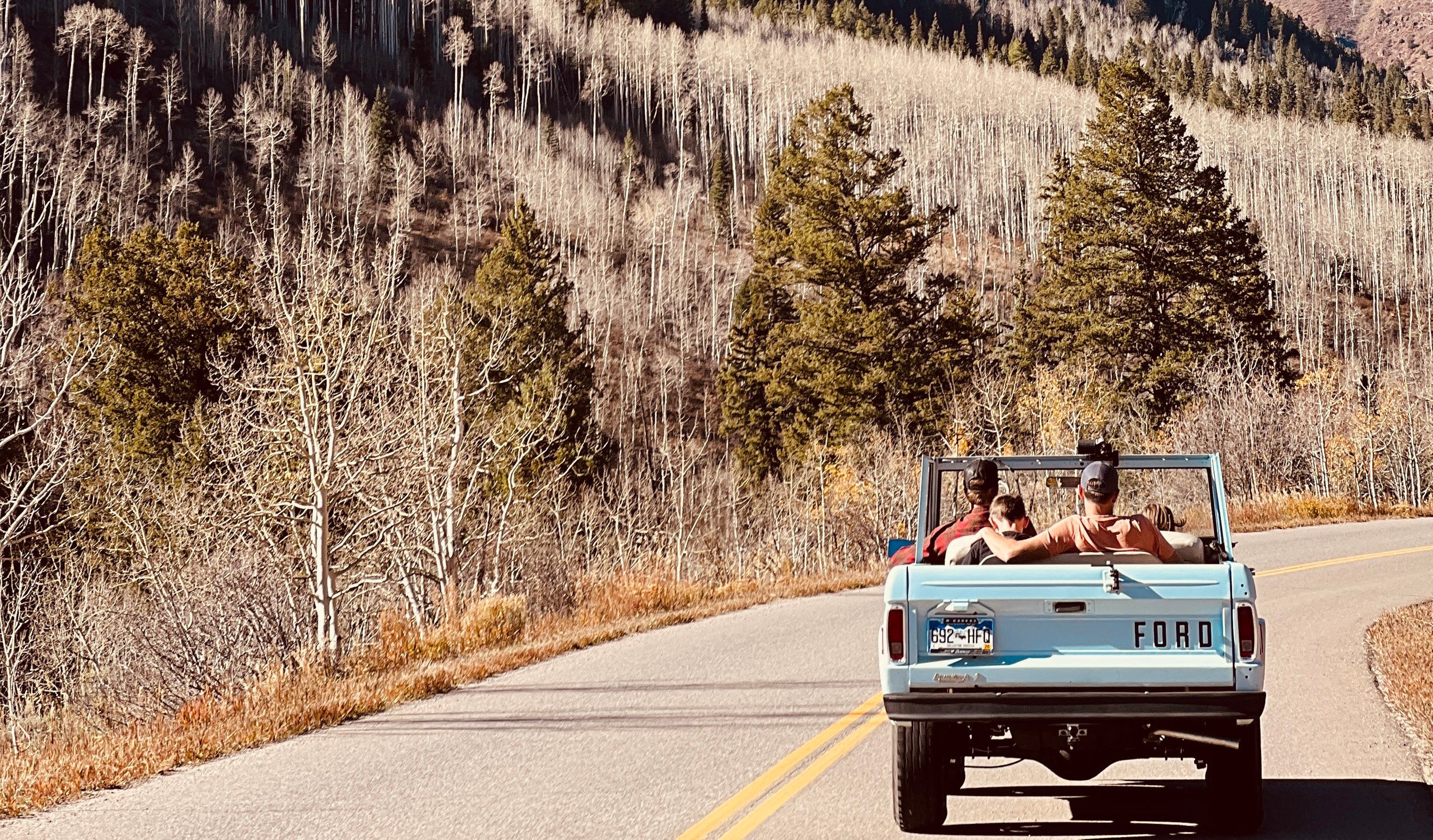 Three guys in a jeep in Colorado wearing baseball hats with dogs on them